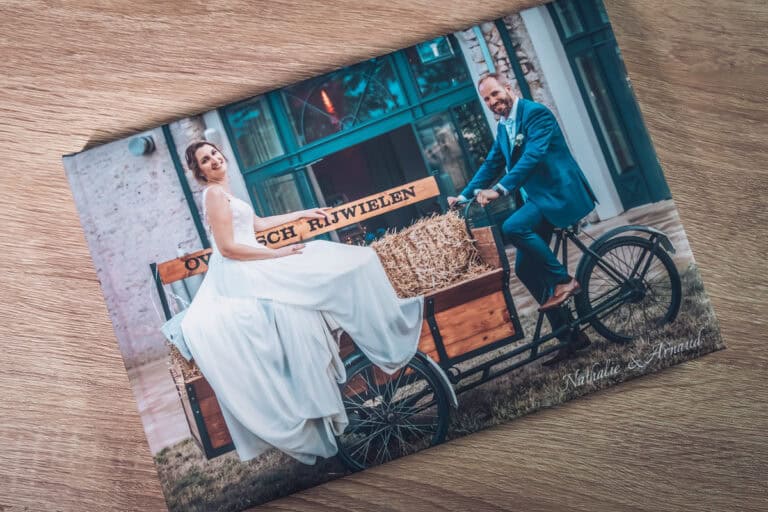 Livre photo de mariage posé sur une table, couverture avec les mariés sur un triporteur