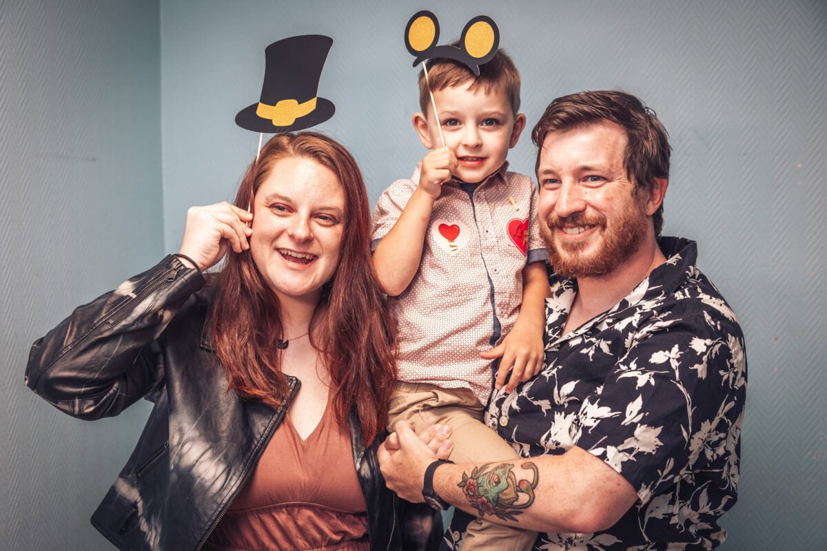 Un couple pose avec un enfant portant des oreilles de souris en carton – mariage de Sophie et Alexandre